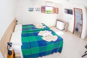 a bedroom with two beds with blue and green sheets at Vila do Galo in Porto De Galinhas