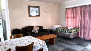 ein Wohnzimmer mit einer Couch und einem Bett in der Unterkunft Takanini Park Motor Lodge in Auckland