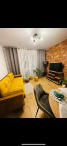 a living room with a yellow couch and a table at Lotus apartments NaturaApart garaż in Ostrołęka