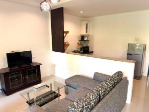 a living room with a couch and a tv at Buncha Place in Bang Tao Beach