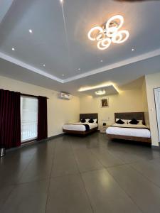 a large room with two beds and a chandelier at Pakalakam Resorts in Cheruppulasseri