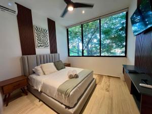 a bedroom with a bed and a desk and windows at Departamento 2 hab con alberca y roof garden en Temozón in Mérida