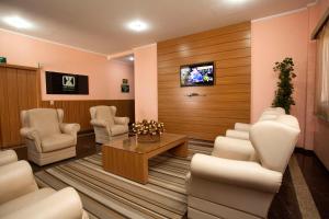 a waiting room with chairs and a tv on a wall at Indaiá Hotel Residence in São Carlos