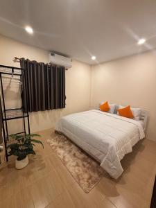 Un dormitorio con una gran cama blanca con almohadas naranjas. en Golden Heaven, en Suratthani