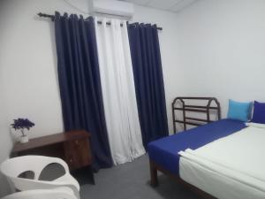 a bedroom with blue curtains and a bed and a chair at Casa Tranquila in Talalla South