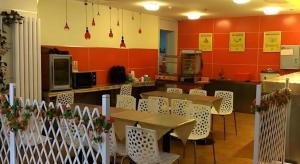 a restaurant with tables and white chairs and red walls at 7 Days Inn Nanjing Railway Station Xin Mo Fan Road Subway Station Branch in Nanjing
