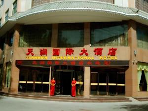 two people in red uniforms standing outside of a building at Tianrun International Hotel in Dunhuang