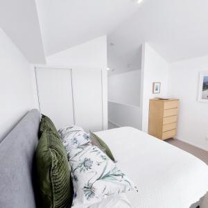 a white bedroom with a bed and a dresser at Villa in the heart of Matakana in Matakana