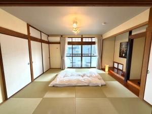 a bedroom with a bed and a large window at かみくまハウス in Kumamoto