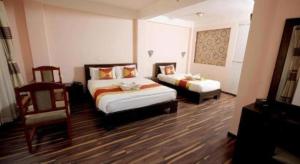 a hotel room with two beds and a chair at De Hotel Veda in Kathmandu