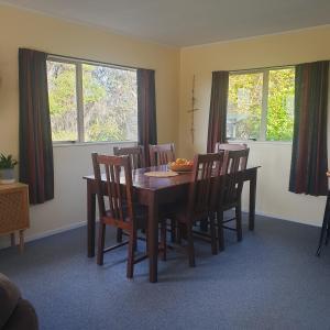 une salle à manger avec une table, des chaises et des fenêtres dans l'établissement Tealuca Holiday Home, à Ngataki 6 autres photos