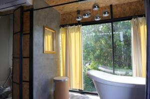 a bathroom with a tub and a large window at Near beach hostel in Bang Tao Beach