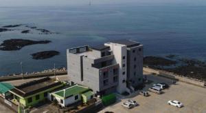 Un gran edificio blanco con coches aparcados frente al agua. en HOTEL52, en Seogwipo
