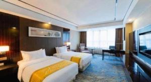 a hotel room with two beds and a flat screen tv at Ramada by Wyndham Wuhu in Wuhu