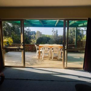Une porte ouverte s'ouvre sur une terrasse avec une table et des chaises. dans l'établissement Tealuca Holiday Home, à Ngataki