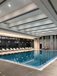 une grande piscine avec des chaises dans un bâtiment dans l'établissement Tashkent City Apartments D11, à Tachkent