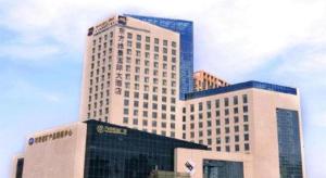 a tall white building with a lot of windows at Ramada by Wyndham Zhengzhou East in Zhengzhou