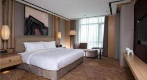 a hotel room with a large bed and a television at Ramada by Wyndham Zhengzhou East in Zhengzhou +53 photos