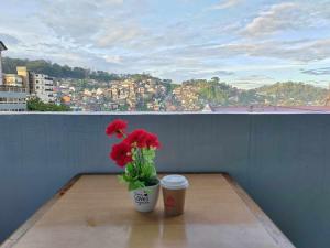 a vase with red flowers and a coffee cup on a table at Your Own Room at a Shared Apartment with Balcony in Baguio