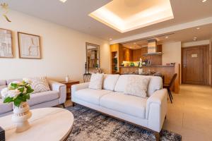 a living room with two white couches and a kitchen at The Palm Retreat 1BR in St Regis Residences Saadiyat in Abu Dhabi +56 photos