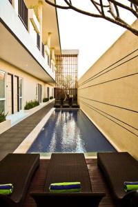 a swimming pool in a building with two loungers at Eazy Suite Legian in Seminyak
