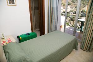 a bedroom with a bed and a balcony with a suitcase at Hotel Villa Bianca Resort in Taormina