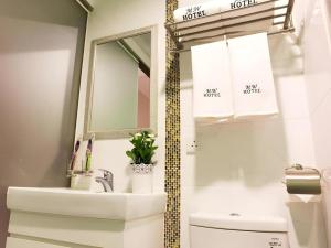 une salle de bain avec un lavabo et un miroir et des toilettes dans l'établissement Metro Winner Hotel, à Hong Kong