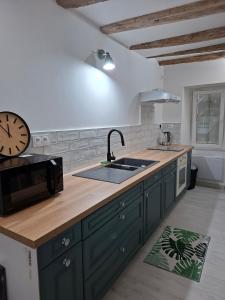 a kitchen with green cabinets and a sink and a clock at Quiet apartment 2 in L'Ile-Bouchard +11 photos