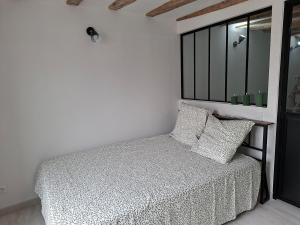 a white bedroom with a bed and a window at appartement calme et climatisé Chamaillard 2 in L'Ile-Bouchard