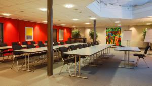 einen Konferenzraum mit Tischen, Stühlen und roten Wänden in der Unterkunft Hotel Belair in Wallisellen