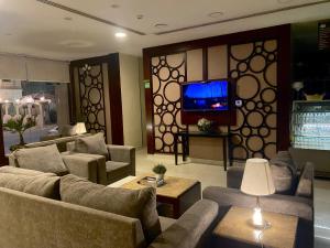 a living room with couches and a flat screen tv at Open Hotel Alolaya in Al Khobar