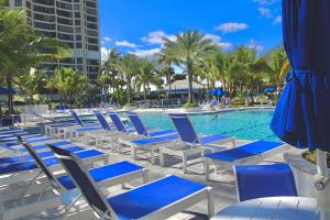 a group of chairs and a swimming pool with palm trees at Seaside Escape in Fort Pierce