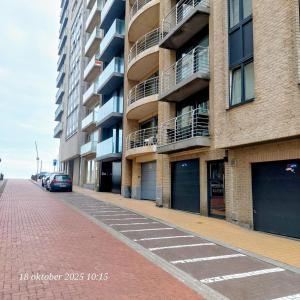 a brick street with cars parked in front of a building at Maison de la mer in Blankenberge