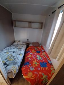 Dormitorio pequeño con cama y edredón colorido en Mobilhome 3 chambre à 2 pas de la plage, en Sarzeau 15 fotos más
