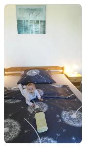 a baby is sitting on a bed at Domeček v Týně pod Helfštýnem in Týn nad Bečvou