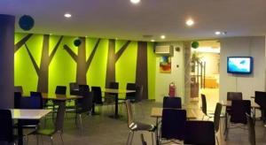 a cafeteria with tables and chairs and a green wall at Casuarina Hotel in Kota Kinabalu