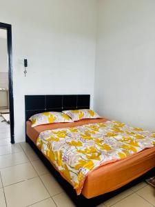 a bedroom with a bed with a yellow and white blanket at Homestay Villa Kepala Batas in Kepala Batas