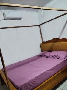 a small bed in a small room with purple sheets at Homestay Mamalis in Bunaken