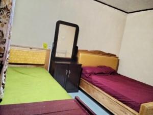 a small room with two beds and a mirror at Homestay Mamalis in Bunaken