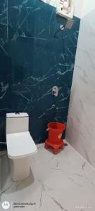 a bathroom with a red toilet and a blue wall at Girbar Dhaam Near By Prem mandir in Vrindāvan