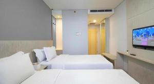 Una habitación de hotel con dos camas y un televisor de pantalla plana. en MIC Residence, en Yogyakarta