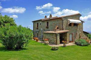 una gran casa de piedra en un campo de hierba en Casale Giacomini, en Manciano