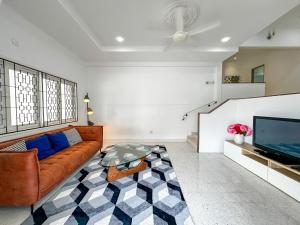 Una sala de estar con un sofá y un televisor. en Modern Garden View Bungalow In Seremban by Maison, en Seremban