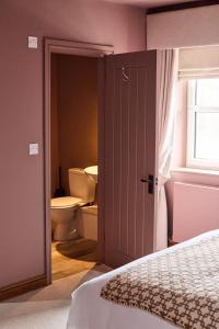 a bathroom with a toilet and a bed and a door at The Bulls Head in Belper +14 photos