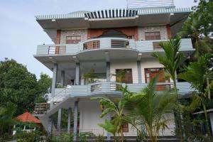 a building with white balconies and palm trees at Avira Cozy Corner in Kilinochchi