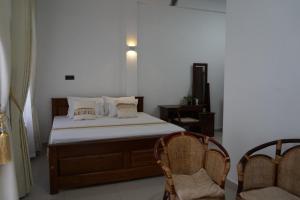 a bed in a room with two chairs and a bed sidx sidx sidx at Avira Cozy Corner in Kilinochchi