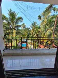 een balkon met uitzicht op palmbomen en een zwembad bij STARFISH Resort in Nagaon