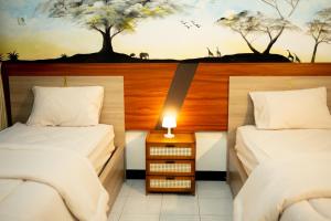 a bedroom with two beds and a wall with trees at Ijen Vibe's Inn in Banyuwangi