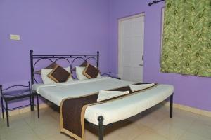 1 dormitorio con 2 camas, paredes de color púrpura y ventana en Libton Manor, en Candolim
