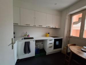 a kitchen with white cabinets and a sink and a table at Schlafmöglichkeit in Luzern
